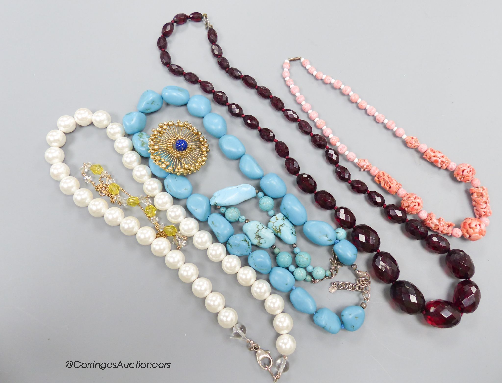 A faceted cherry 'amber' necklace, three other necklaces, 2 bracelets and a brooch